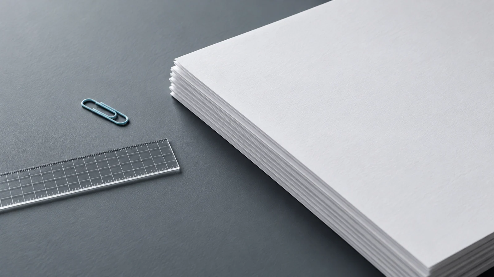 Blank paper forms beside a transparent ruler and an ice-blue paperclip.